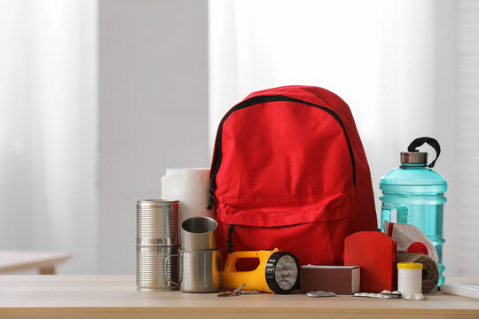 Red emergency backpack with necessities on table in room