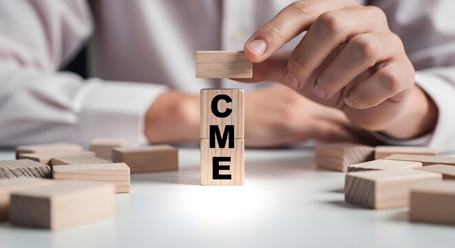 Cme acronym on stacked wooden blocks being held by a hand, representing trading or education, continuous medical education