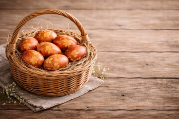 Obraz premium Naturally dyed onion skin Easter eggs in rustic wicker basket with copy space