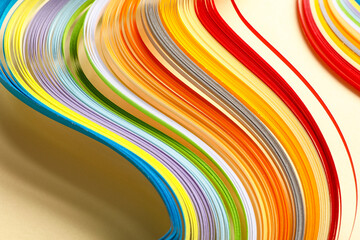 Fototapeta premium Colorful paper strips for quilling on beige background, closeup