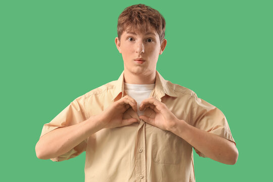 Surprised young man with imaginary binoculars on green background