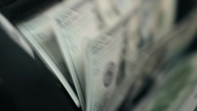 High-value $100 bills being automatically counted in modern money counter. Finance and cash handling concept.
