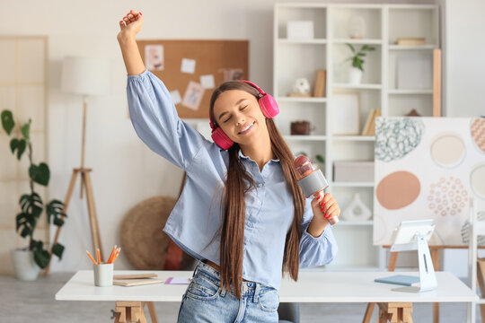 Teenage girl in headphones with microphone singing at home