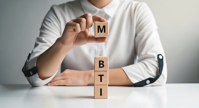 Person holding a wooden block with 'm' above stacked blocks spelling 'bti', symbolizing mbti personality types, human resources