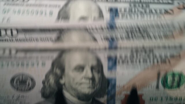 Close-up of stacked $100 bills moving through counting machine. Banking and business concept.
