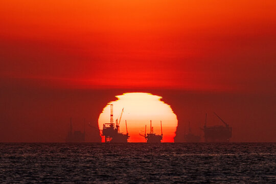 Sunset behind offshore oil platforms on the coast of Santa Barbara, California