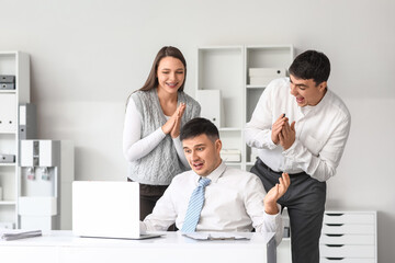 Obraz premium Shocked young man with drawn mustache and his colleagues in office. April Fools' Day celebration