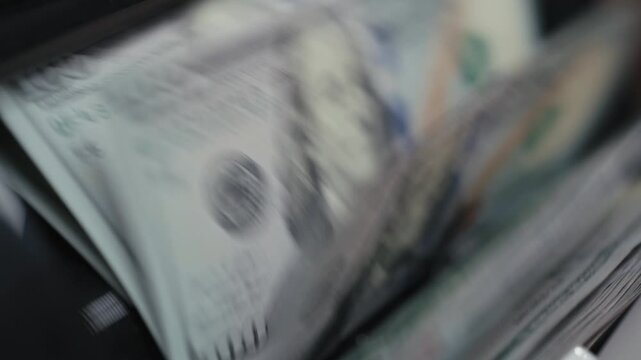 Close-up of $100 bills being counted by electronic money counter. Finance and banking concept.
