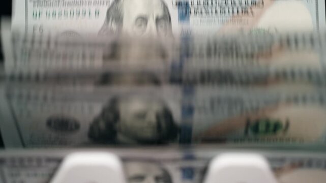 Money counter in action with crisp $100 bills stacked neatly. Cash management concept.
