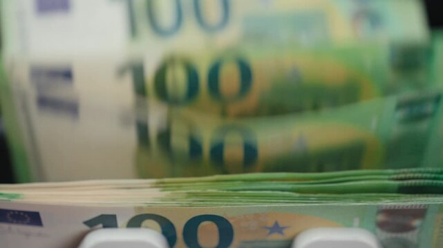 Close-up sequence of euro banknotes being processed through a currency counting machine, showcasing the flow and movement of cash in a financial setting