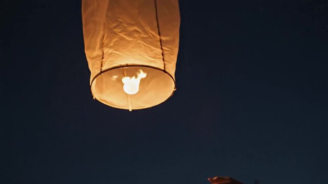Asian woman in traditional attire gently releases a glowing lantern into the night sky, with her hands positioned carefully, surrounded by a starry backdrop creating a serene atmosphere