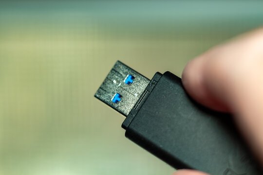 A modern black usb flash drive held by a hand in blurred background for data transfer technology concepts