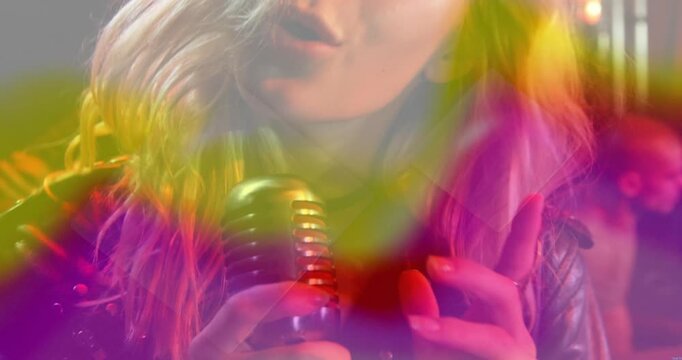 Music singer starting soft phrasing, building sustained singing while neon colors drifting over mic