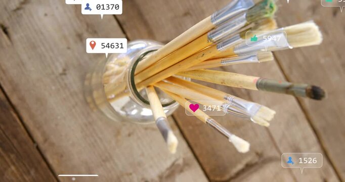 Paintbrushes in glass jar rotating over wood table, badges popping up and signaling marketing