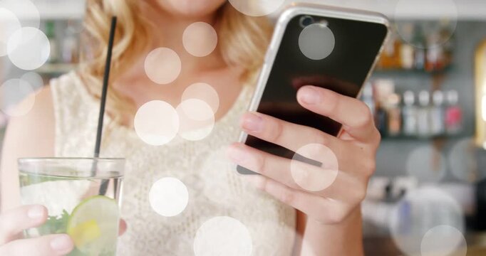 Woman tapping phone, showing lime mint glass and placing drink at bar, bokeh guiding focus