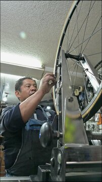 Skilled technician adjusting spokes for bicycle wheel alignment