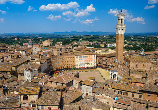 A panoramic view over Piazza del Campo, the heart of Siena, surrounded by medieval buildings and dominated by the Torre del Mangia. 