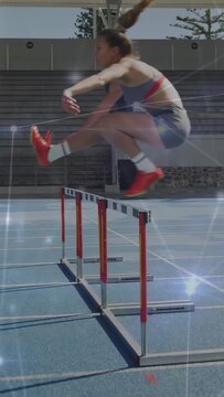 Vertical video: Athletics hurdler sprinting on blue track approaching, clearing hurdle with sparkle