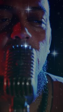 Vertical video: Male singer singing into mic, camera pulling back, stars highlighting face in music