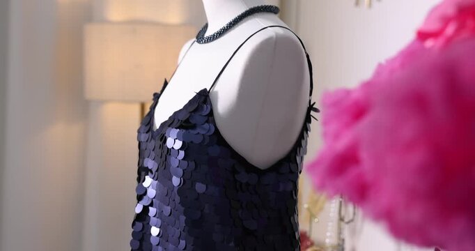 Different festive clothes hanging on racks and female mannequin with stylish dress indoors, closeup. Camera moving forward and up