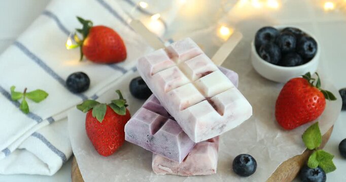 Woman putting delicious yogurt popsicle onto table, closeup