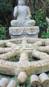A serene Buddha statue sits in meditation pose, surrounded by deer sculptures and a Dharma wheel, symbolizing Buddhist teachings in Marble Mountain, Da Nang, Vietnam.