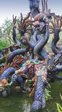 A dragon sculpture sits in a pond at the Phuc Kien Assembly Hall in the historic city of Hoi An, Vietnam. The dragons are a symbol of power, strength, and good fortune.
