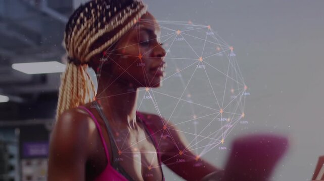 African American woman in pink top gripping elliptical, pedaling at gym, smartwatch showing network