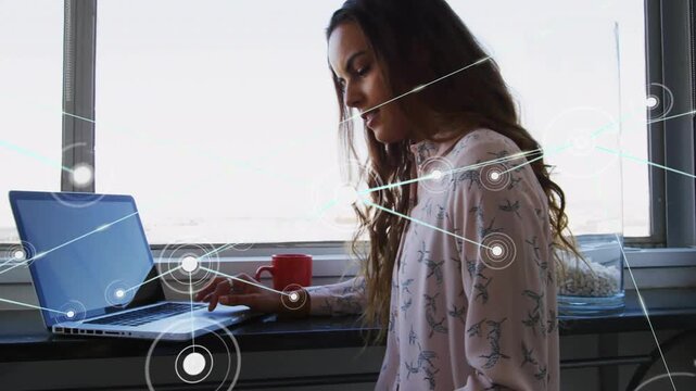 Woman placing sketch then tapping laptop, activating network overlay while organizing design notes