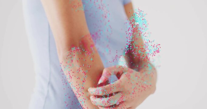 Hands joining at waist causing cyan-magenta particles, woman rubbing right forearm showing relief