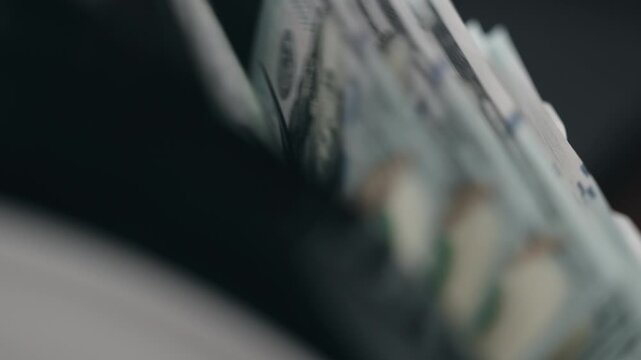 Close-up of $100 bills being sorted and counted in money counter. Banking concept.
