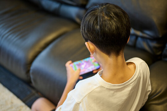 スマホゲームに夢中の男の子の後ろ姿