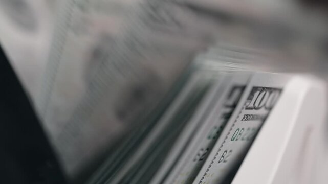 Counting one hundred dollar bills in high-speed money counter with display. Accounting concept.
