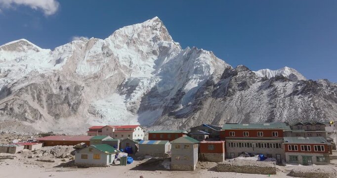 Aerial drone shot of Gorakshep village at 5100 meters with trekkers lodges beside Khumbu Glacier and towering Everest, Nuptse and Lhotse peaks along the Everest Base Camp trekking route in Nepal.