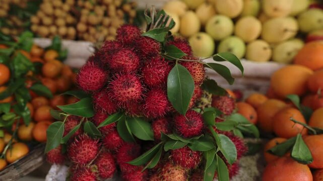 Rambutan Cluster Vietnam Street Market Vibrant Tropical Fruit Display With Green Leaves, Oranges And Longan In Crates, Wooden Stall, Morning Light, Fresh Textures And Juicy Appearance