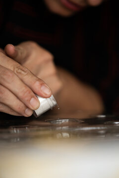 Manos espolvoreando brillo comestible en moldes de chocolate, proceso creativo en cocina gourmet