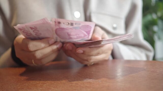 Woman hands counting two hundred turkish lira banknotes slow motion close up, concept of economy, finance, and investment