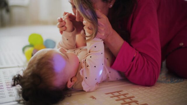 Mother lying on floor interacting with her baby during playtime at home