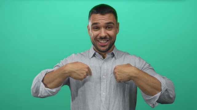 Man smiling and pointing finger to chest wearing striped shirt in green studio; confidence self belief.