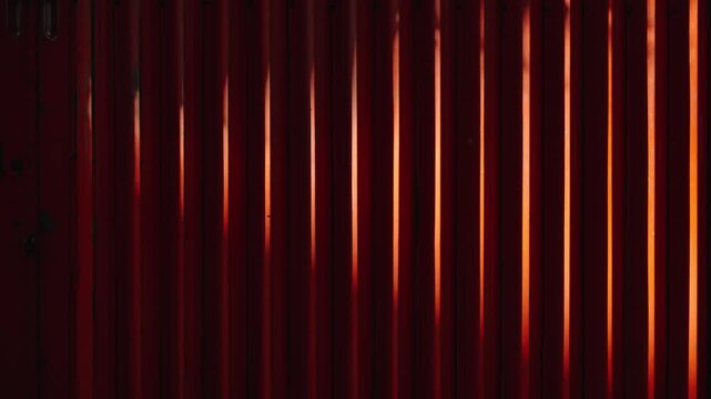 Static shot of red metal gate texture with diagonal sunlight streaks, abstract urban pattern background for cinematic and design use