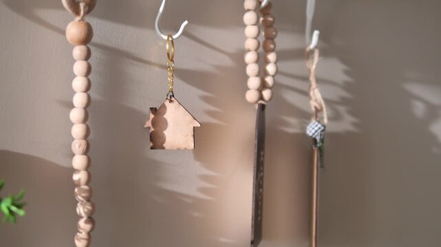 Wooden house keychain and bead decor hanging on wall hooks in cinematic sunlight