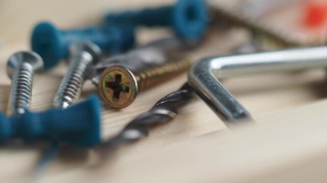 Macro view of hardware tools screws and drill bits on wooden surface with rack focus effect