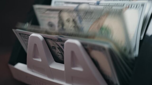 Cash counting machine displaying stacks of hundred-dollar bills in a continuous flow, showcasing the organized arrangement of currency in a financial setting