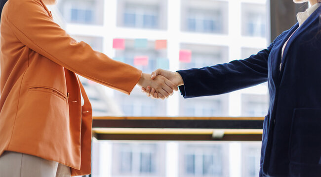 A detailed image of two professionals shaking hands, focusing on the significance of their deal in a bright office setting that encourages collaboration and synergy.