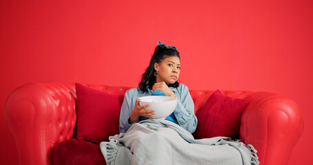 Woman, watching tv and popcorn with sofa on studio with portrait, scared and space on red...