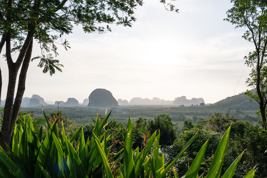 Limestone karst mountains and tropical jungle at sunrise in Krabi Thailand framed by trees