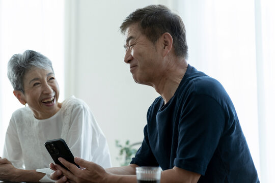 スマートフォンを見ながら談笑する日本人シニア夫婦