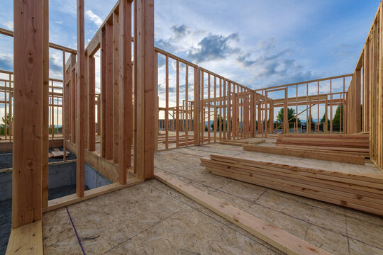 A new home in the framing phrase of residential construction with walls built and a concrete foundation for structural support.