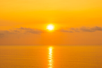 Obraz premium nature sky breathtaking golden sunset over a calm ocean, with the entire sky and water bathed in brilliant shades of yellow and orange. Streaky clouds enhance the dramatic display 