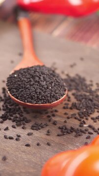 Close up slow motion video of black nigella seeds in a wooden spoon, perfect for culinary and health-related projects